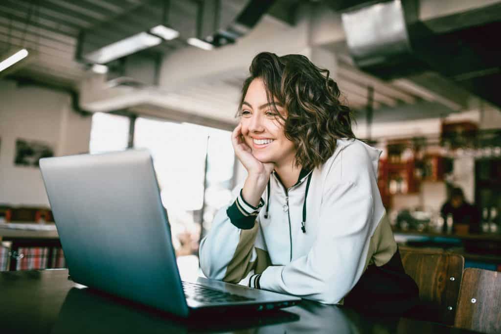Uśmiechnięta kobieta siedzi przed laptopem